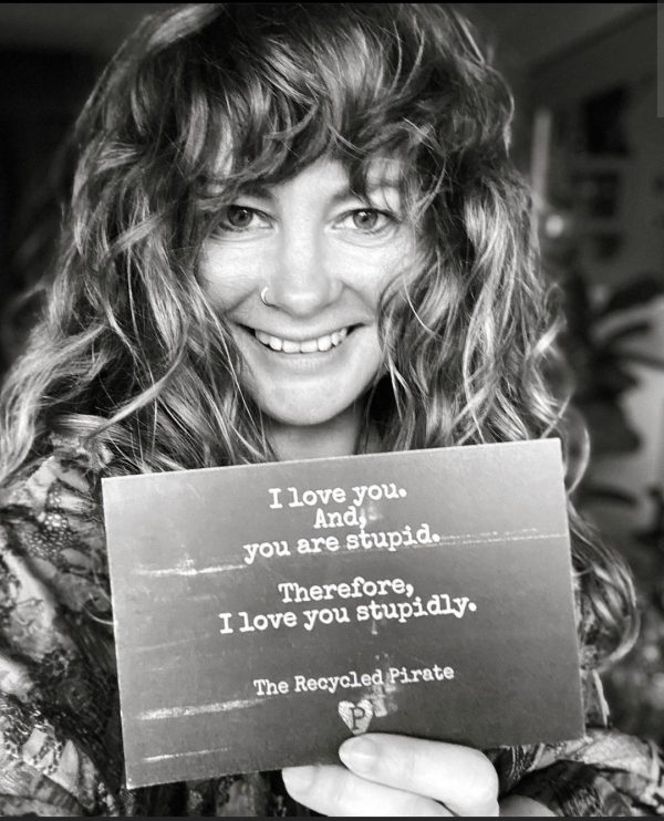 Melanie Mudde, the Netherlands, Haarlem. holding a recycled paper postcard by The Recycled Pirate; I love you, and you are stupid,. Therefore, I love you stupidly.